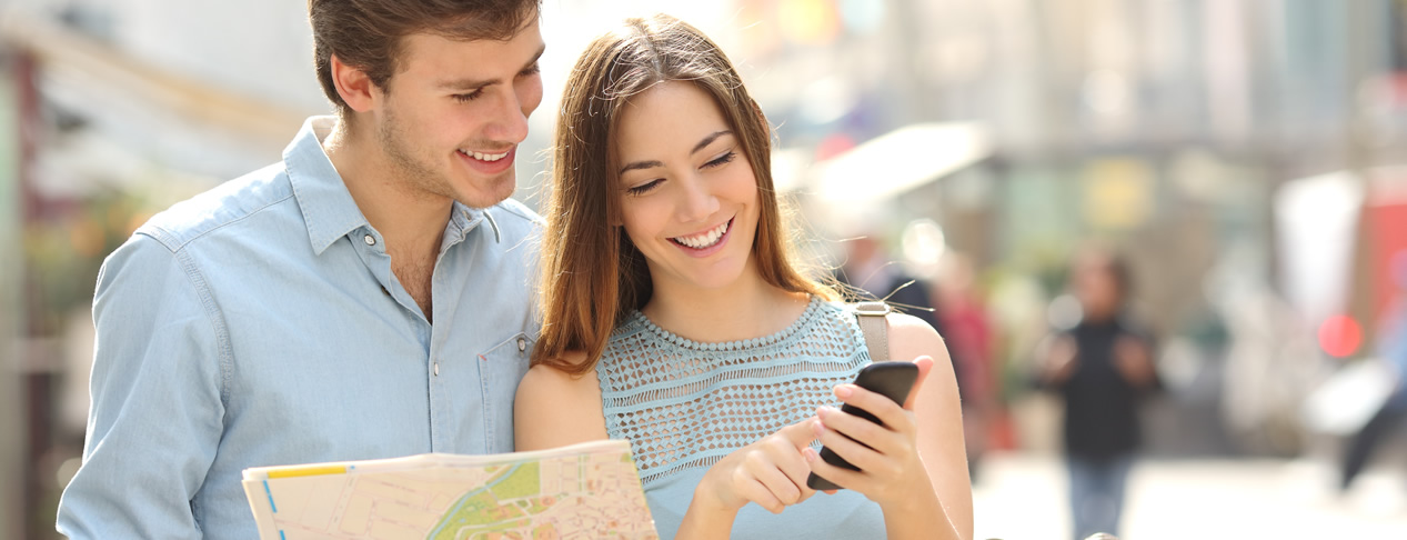 Turistas consultando un plano y una aplicación de GPS en su teléfono móvil.